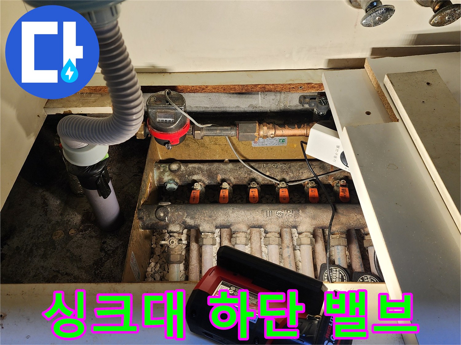 싱크대 아래에 위치한-수도 계량기와 여러 개의 밸브입니다.