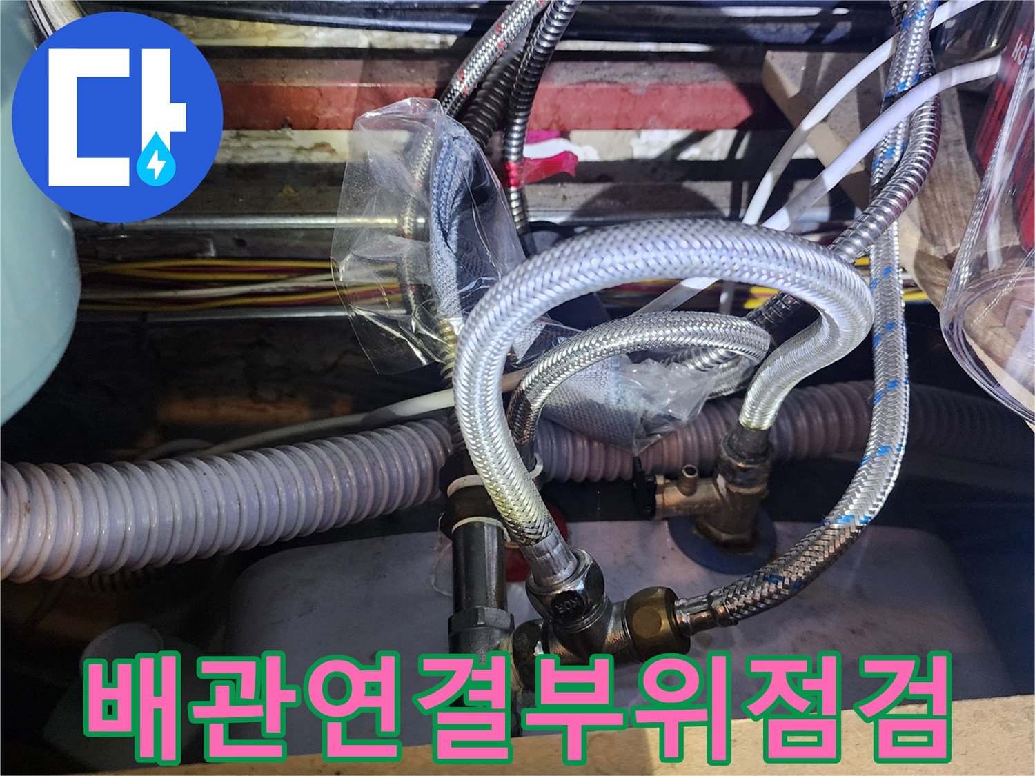 주방 하부장 내부-금속 밸브와 유연한 은색 호스 연결 부위 사진