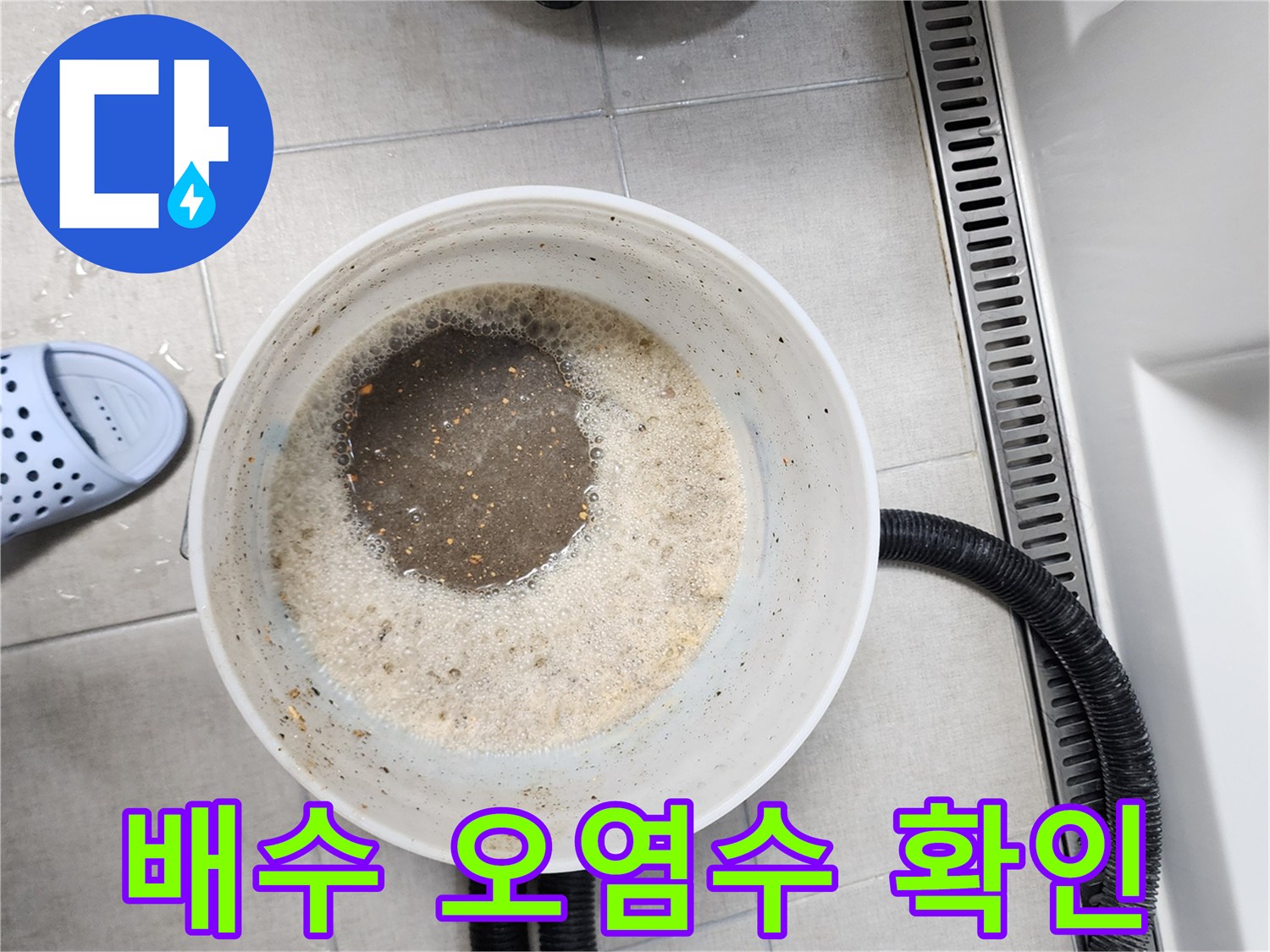 하얀 양동이에 담긴 배수구 오염수와 검은색 흡입 호스