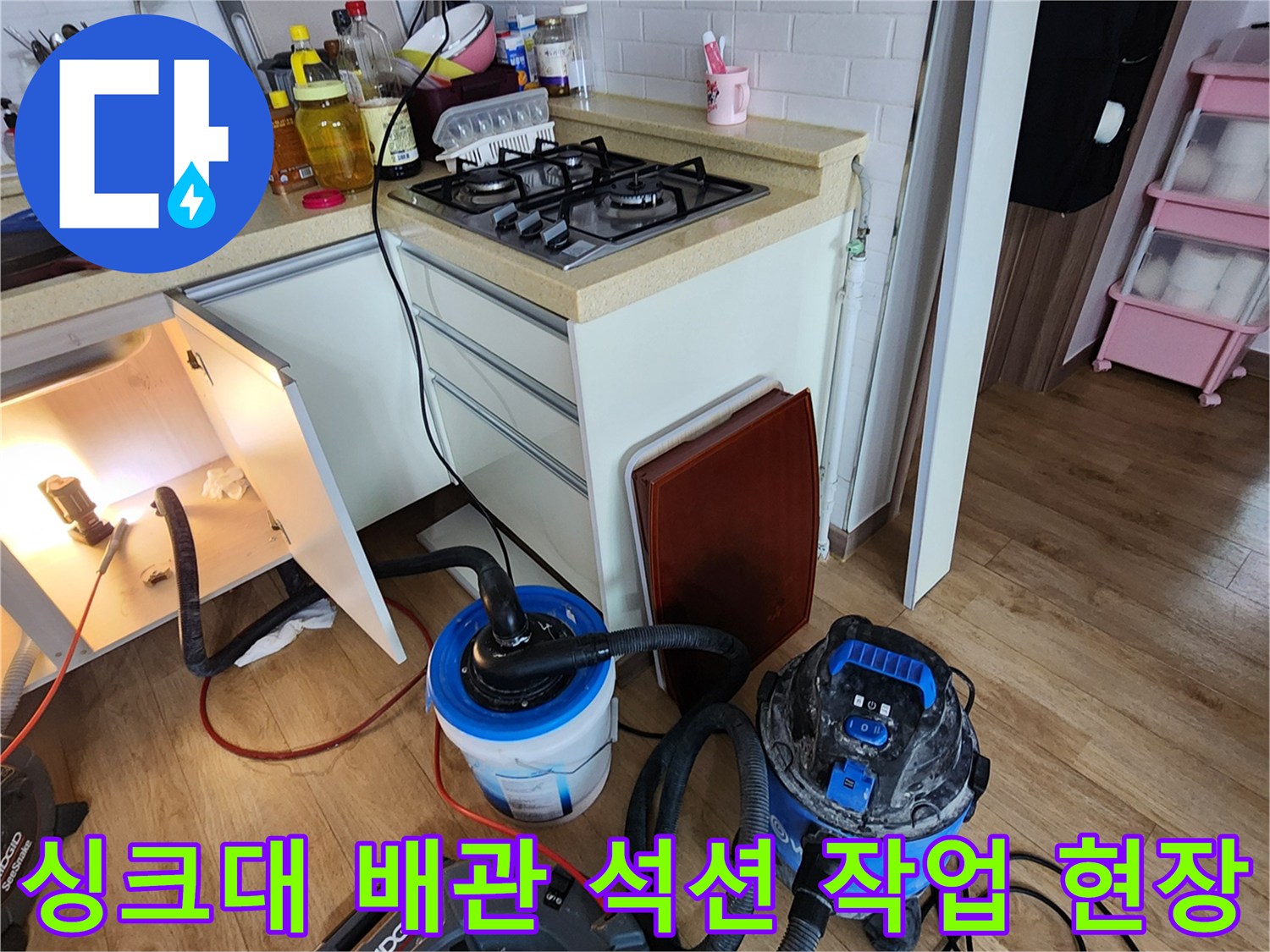 싱크대 아래쪽 공간에서 진행 중인 배관 청소 장비 모습