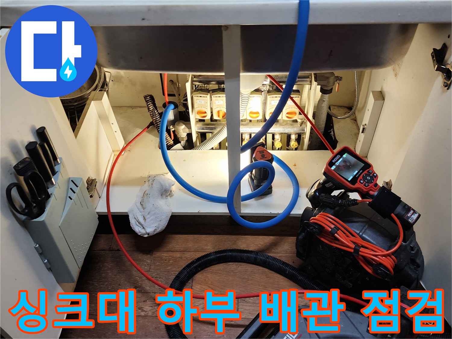 싱크대 하부장 내부의 배관과 전문 진단 장비 모습