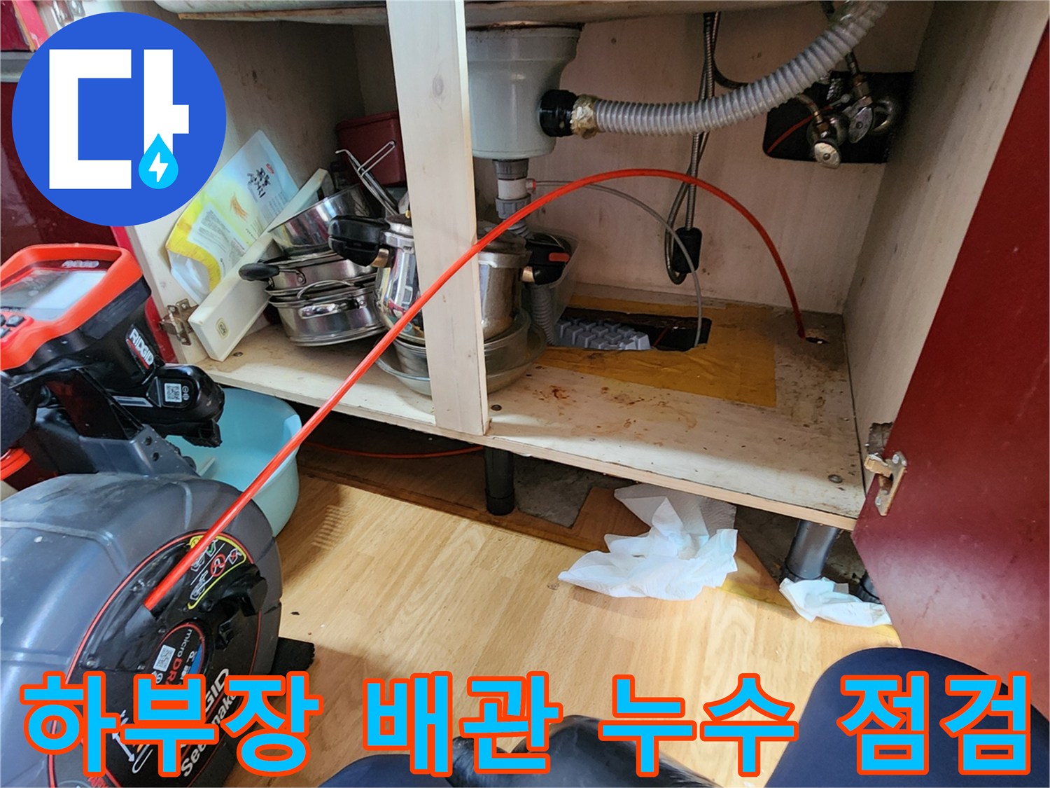 싱크대 하단 내부-누수 지점을 찾기 위해 배관을 조사하는 모습