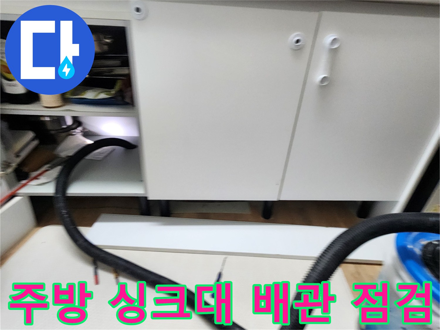 싱크대 하단부의 배관과 주변 장비가 보이는 현장 사진입니다.