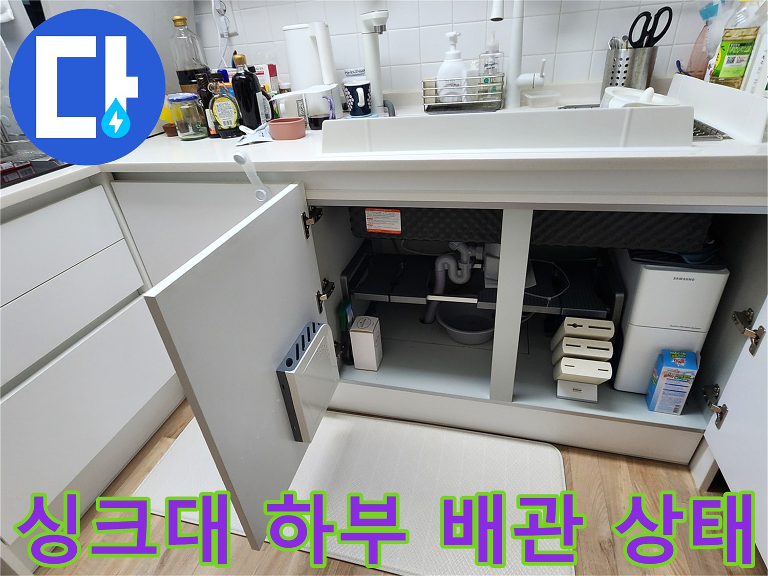 주방 싱크대 아래쪽의 배관 연결부를 촬영한 사진입니다.