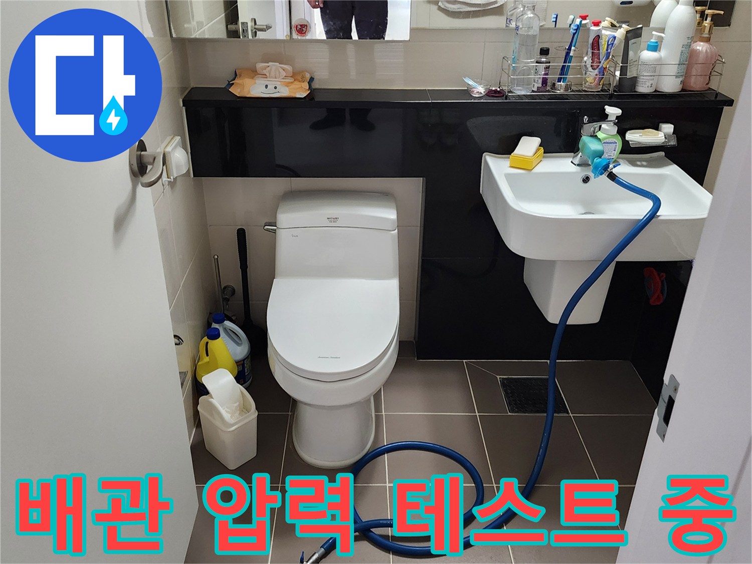 세면대 아래로 길게 연결된 파란색 점검용 호스 모습