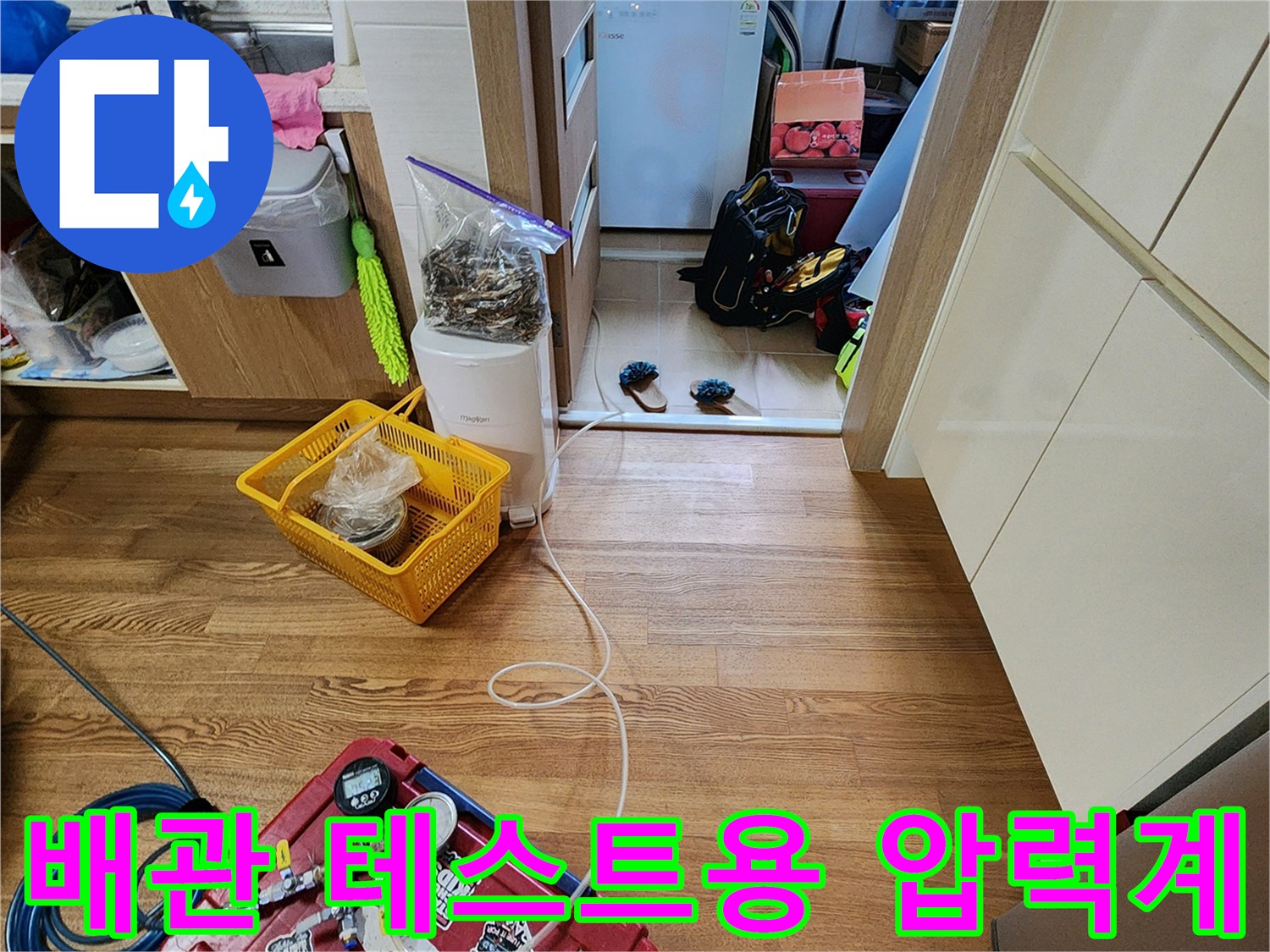 바닥에 놓인 배관 압력 측정 장치와 연결된 파란색 에어 호스