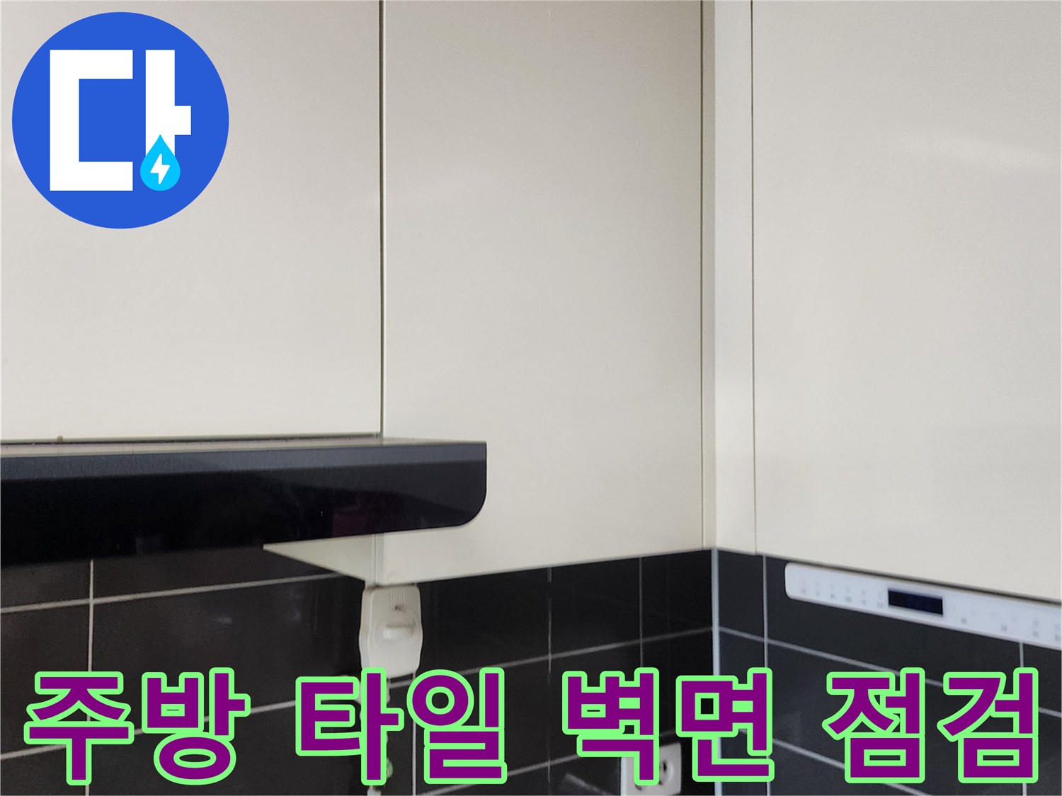 싱크대 하단 타일 벽면과 전기 콘센트 부위의 근접 촬영