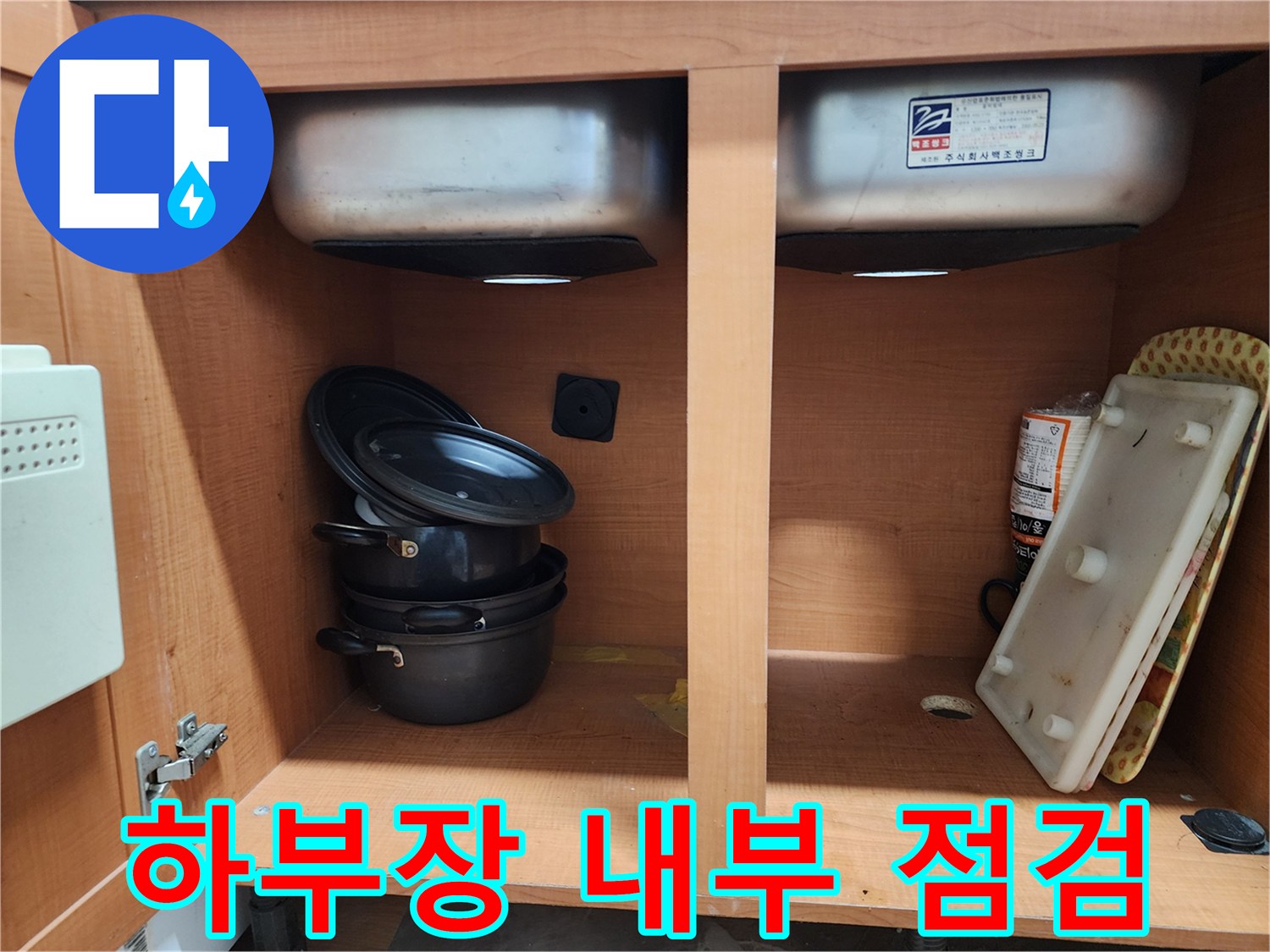 싱크대 하부장 내부 - 누수 원인을 찾기 위해 집중하고 있습니다.