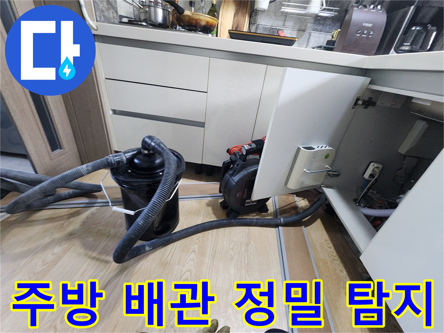 싱크대 하부 가구 안쪽의 배관과 연결된 굵은 흡입 호스