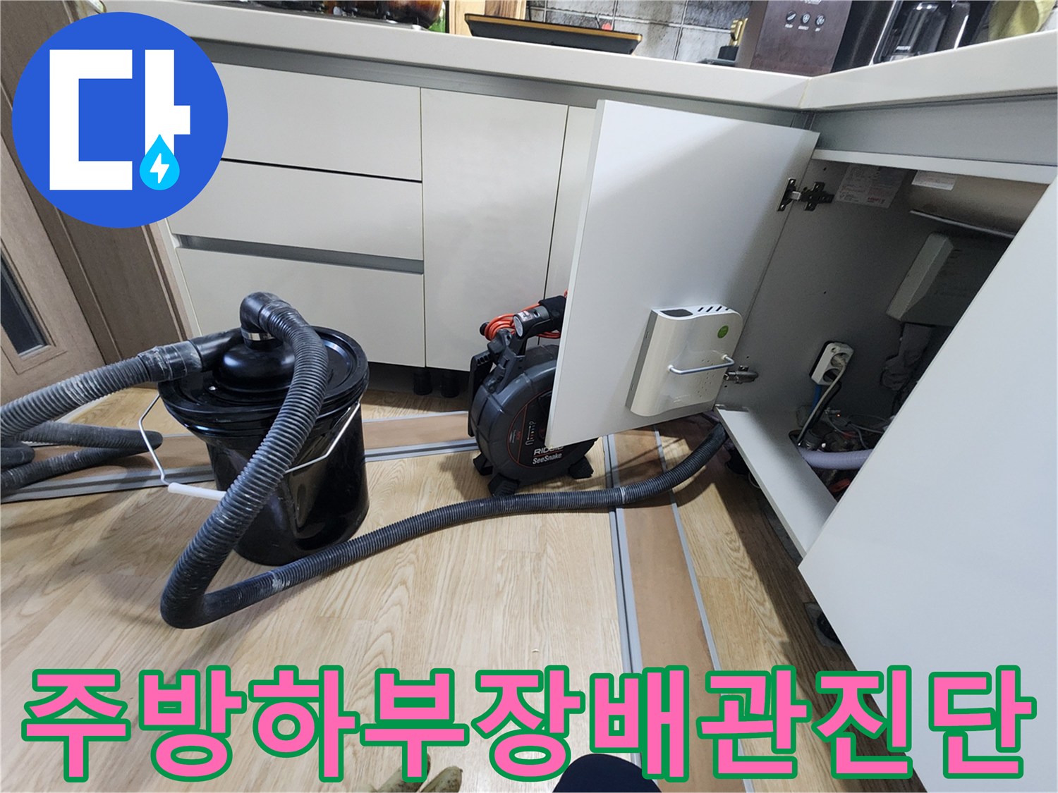 열린 주방 하부장 내부의 배관 구조와 작업 장비 배치