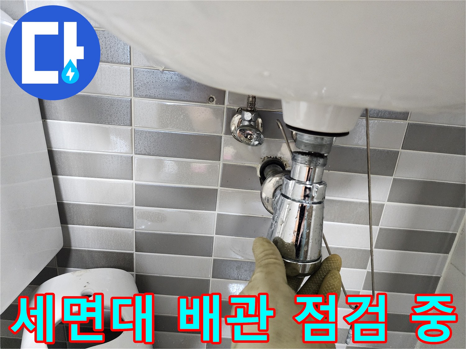 작업자가 세면대 하단 배관 연결 부위를 손으로 만져보며 확인