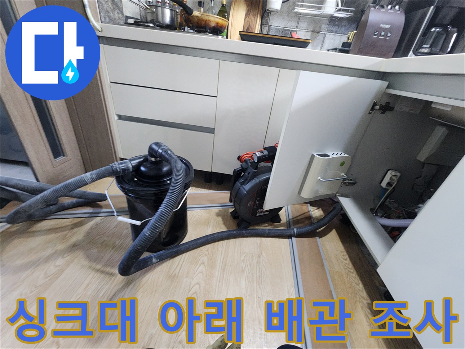 주방 싱크대 하부장 내부의 복잡한 배관과 탐지용 호스 연결 상태