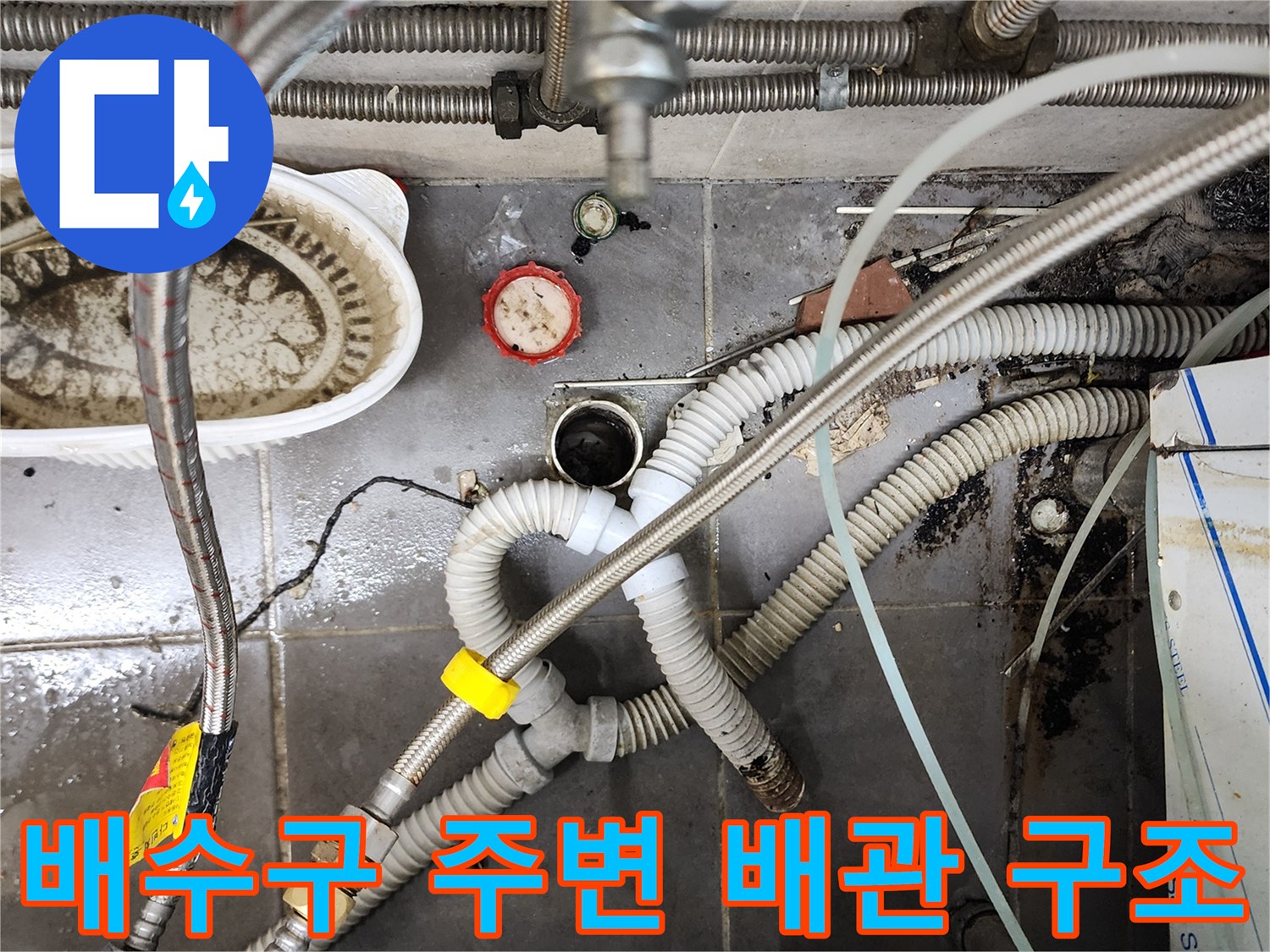 복잡하게 얽힌 주방용 배수 호스와 금속 배관의 연결 상태