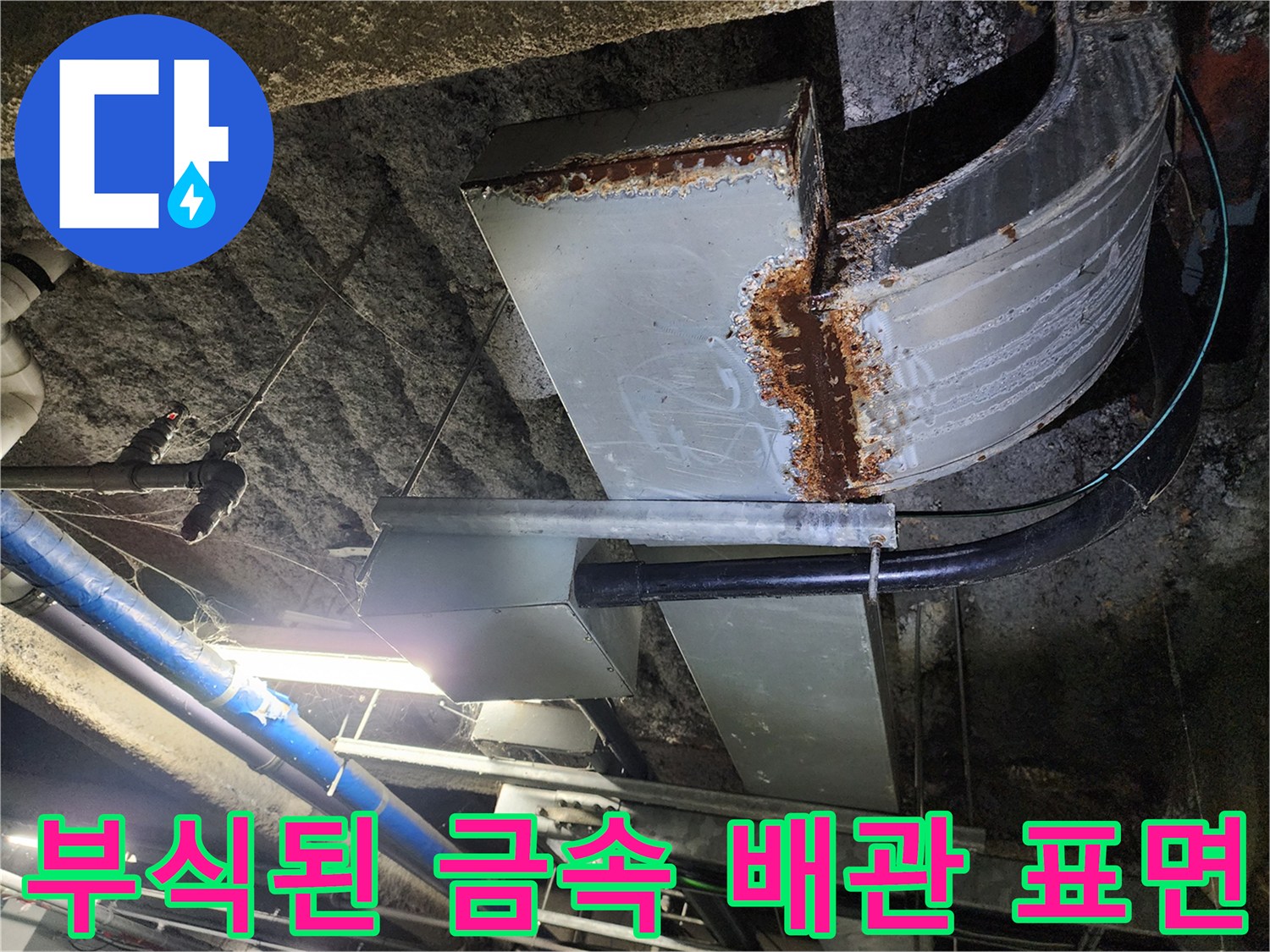 천장 내부의 부식된 배관과 녹물이 묻은 연결 부위입니다.
