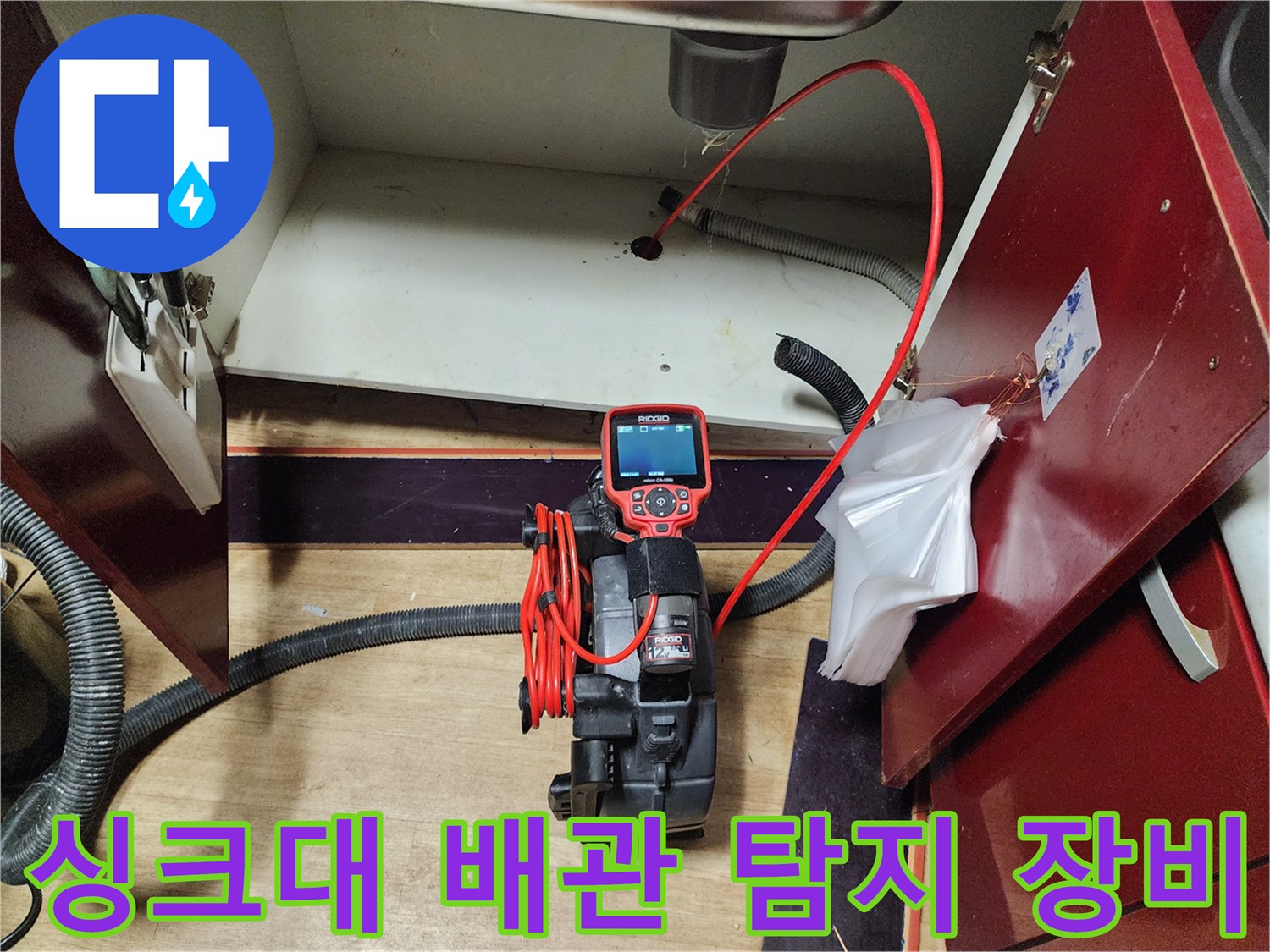 싱크대 하부장 내부의 배관 상태를 점검 중인 내시경 카메라와 전선