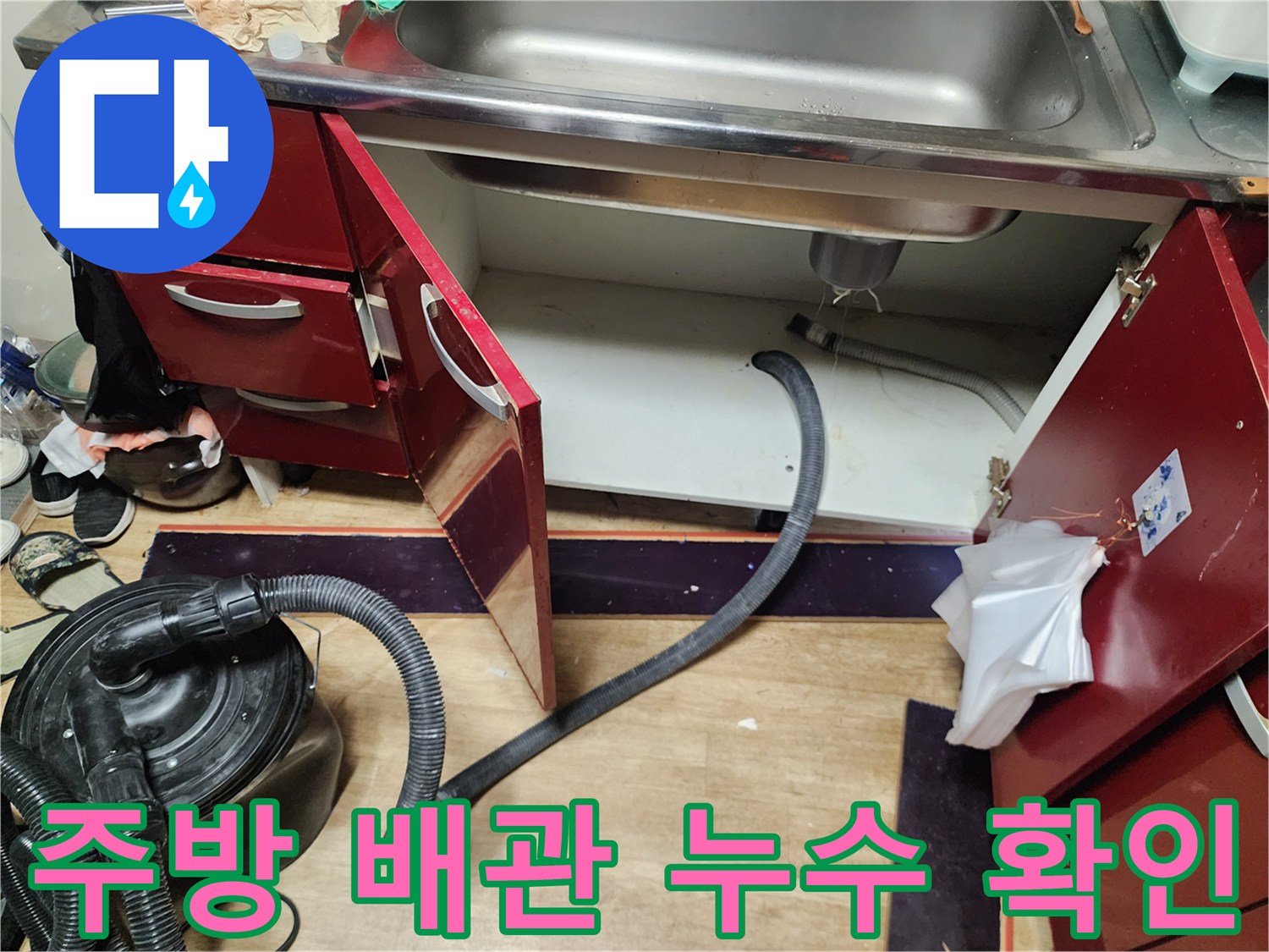 열려 있는 싱크대 하부장 내부와 배수 호스 모습