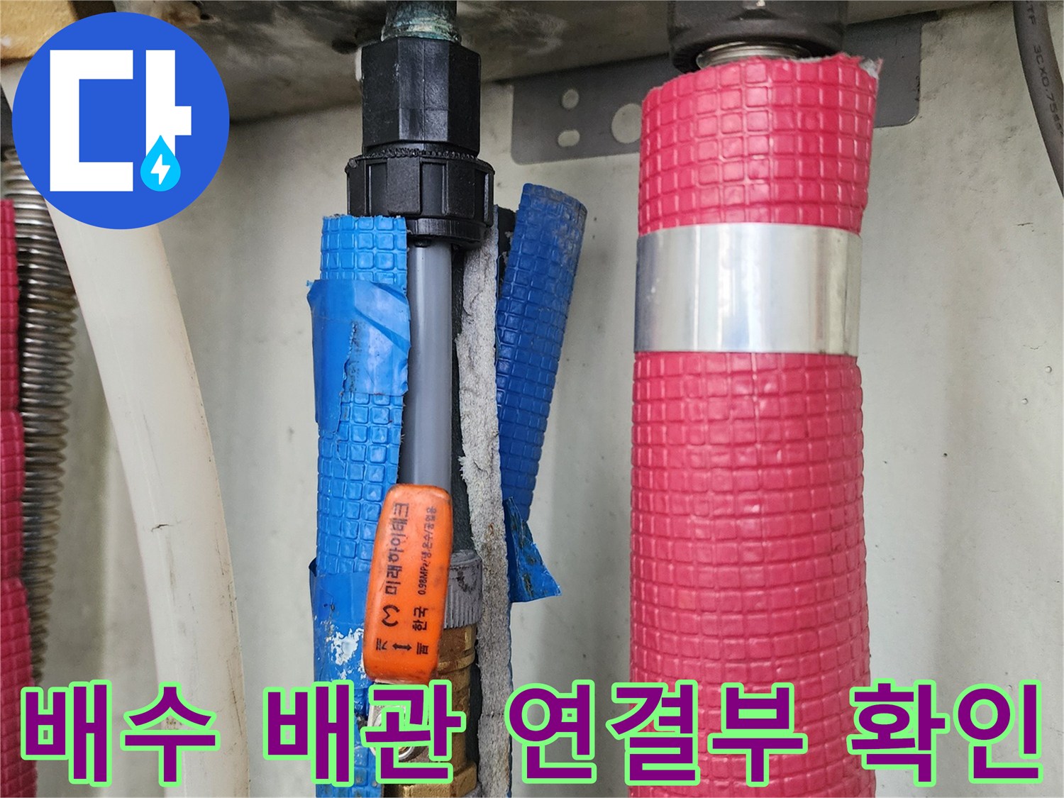 싱크대 하부의 분홍색과 파란색 보온재가 씌워진 배관 연결 부위