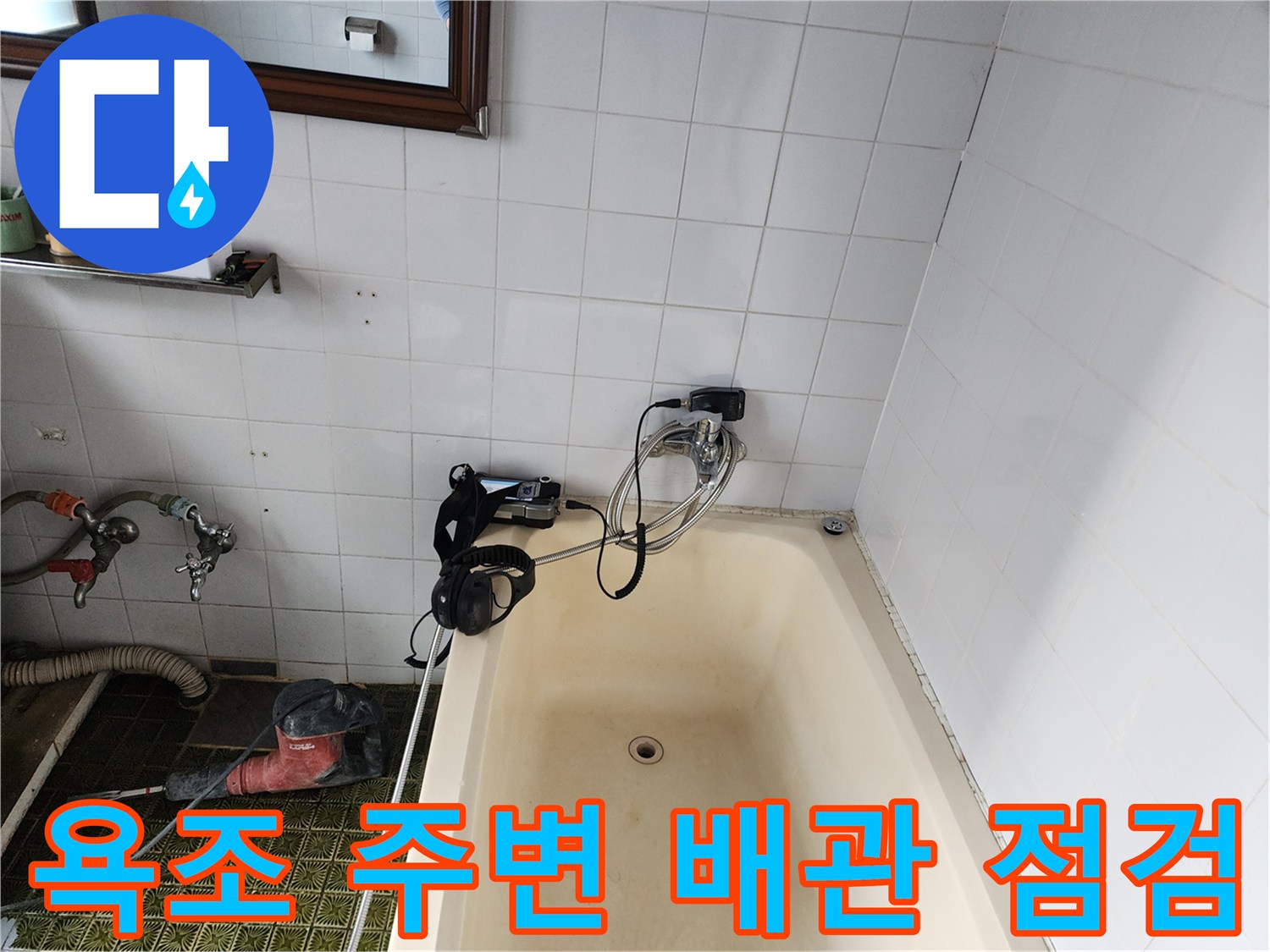 욕조와 벽체 사이 배관 연결부에 탐지용 호스와 압력 측정 장비를 배치한 장면입니다.