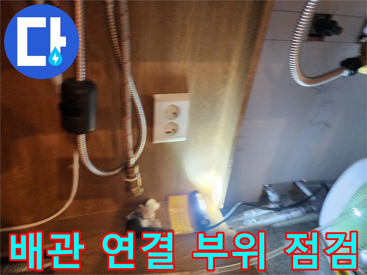 주방 싱크대 하부의 전기 온수기와 배관 연결 상태 사진