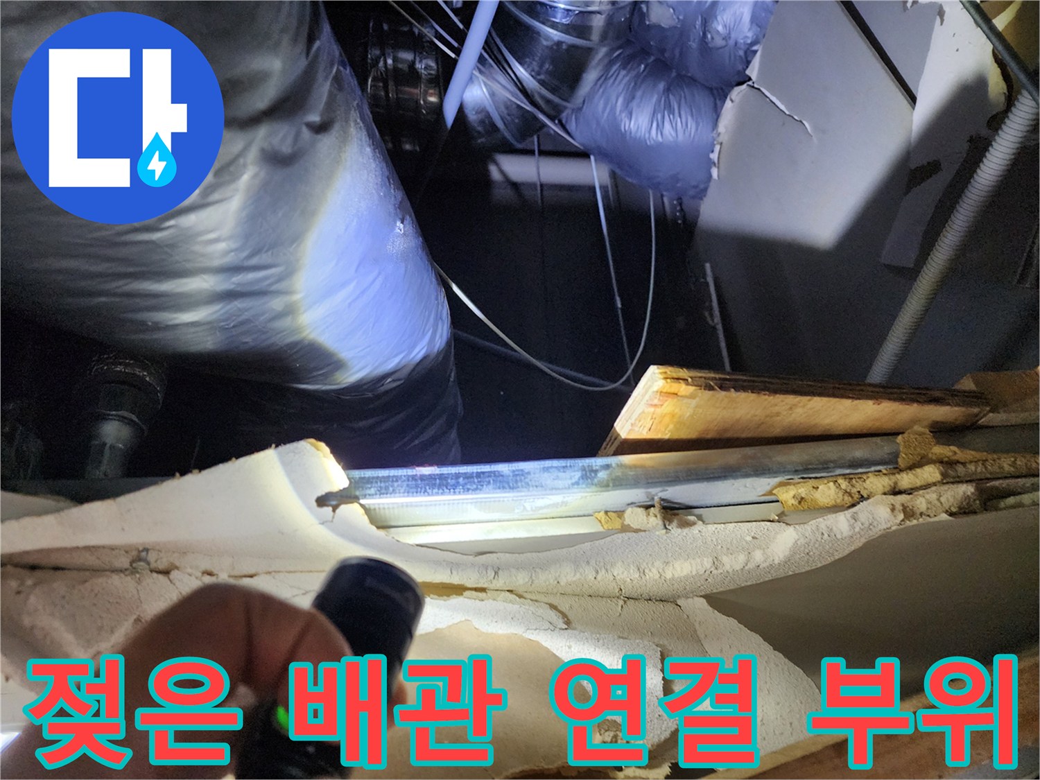 손전등을 사용하여 배관의 누수 흔적을 찾는 작업 장면