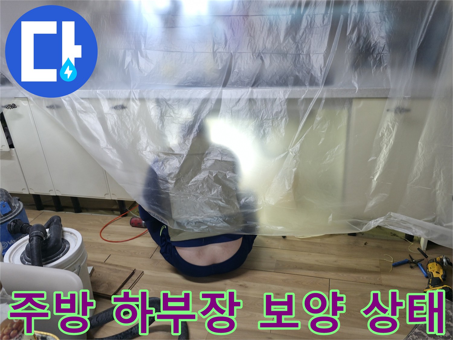싱크대 아래쪽 공간을 비닐로 덮어 작업 환경을 조성한 사진입니다.