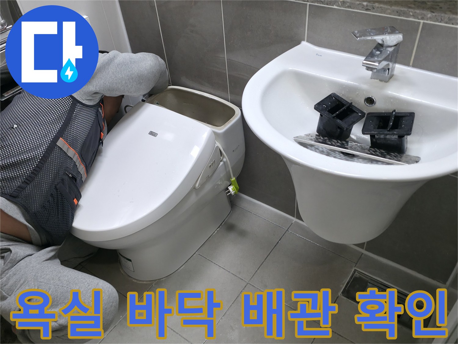 세면대와 변기 사이 타일 틈새를 점검하는 작업 모습