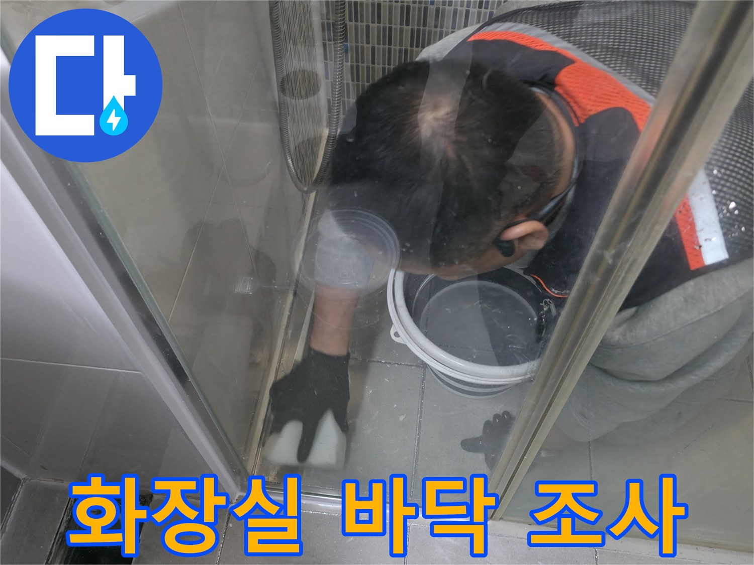 작업자가 엎드려 샤워부스 내부의 타일 균열을 확인하고 있습니다.
