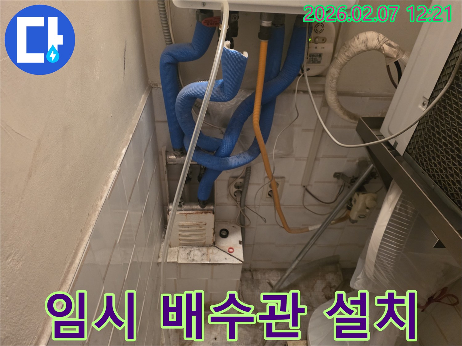 누수 지점에서 물을 임시로-배출하기 위해 설치된-투명한 배수관과-주변 배관들을 점검하는 모습입니다.
