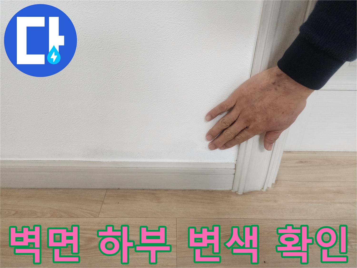 손으로 벽지의 어두운 부분을 가리키며 상태를 체크하는 장면