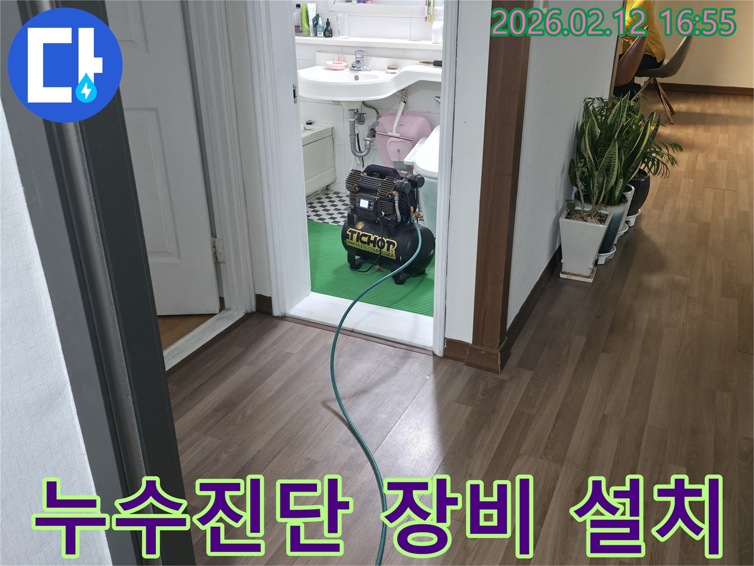욕실 문간에-설치된 누수-탐지 장비와-연결된 호스가-바닥을 지나-누수진단을-위한-정밀 검사-준비 과정