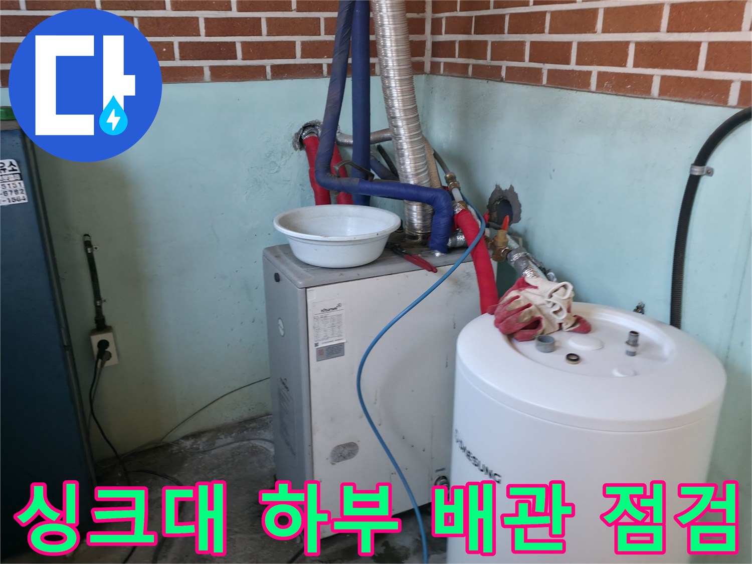 벽돌 벽면 아래 - 연결된 은색 배관과 온수기 모습