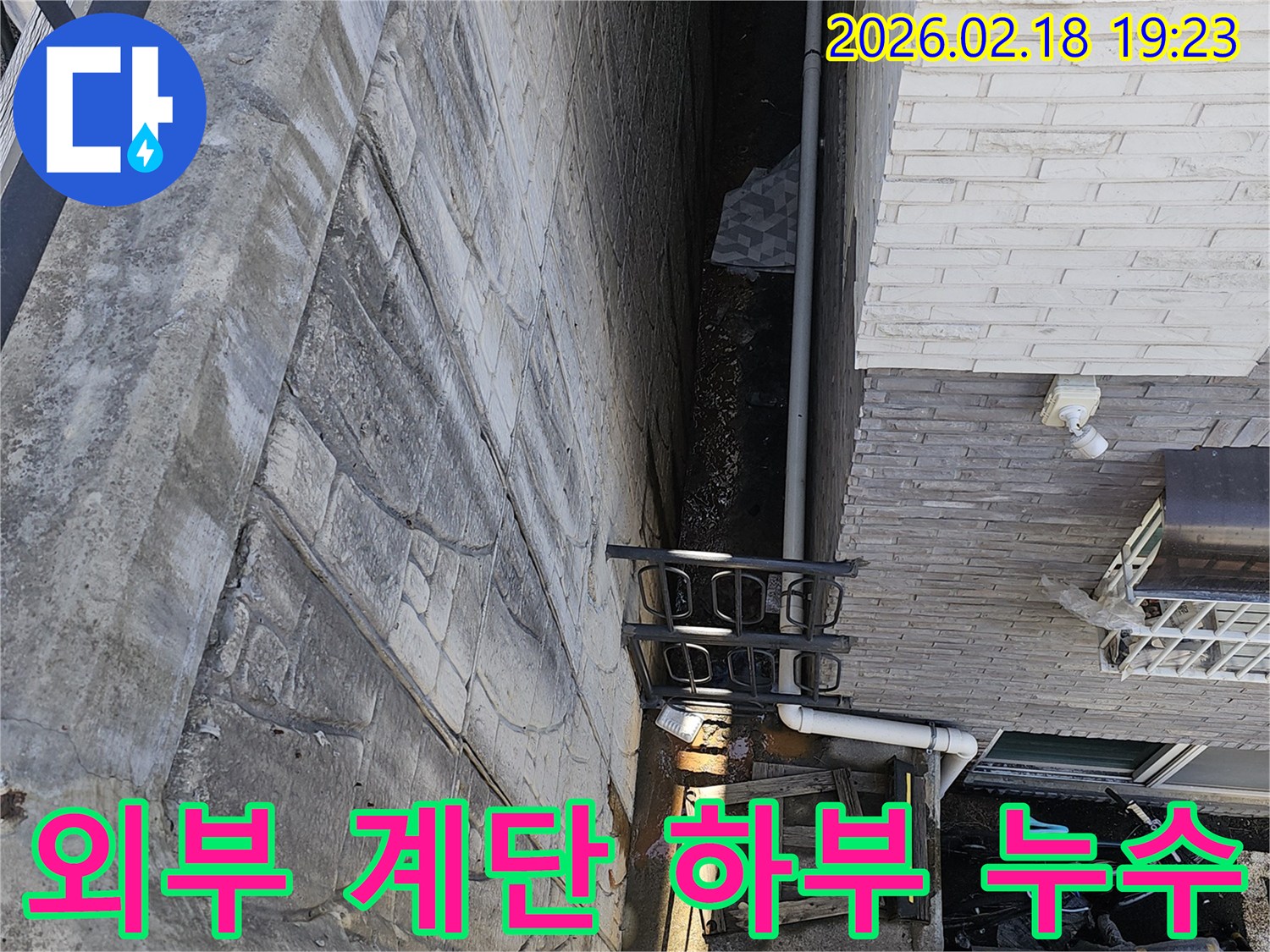 고양시 숲속마을 주택 외부 계단 하부에서 발생한 누수 문제를-해결하기 위한 방안을 모색하기 위해 전문가가 현장을 진단하는 모습입니다