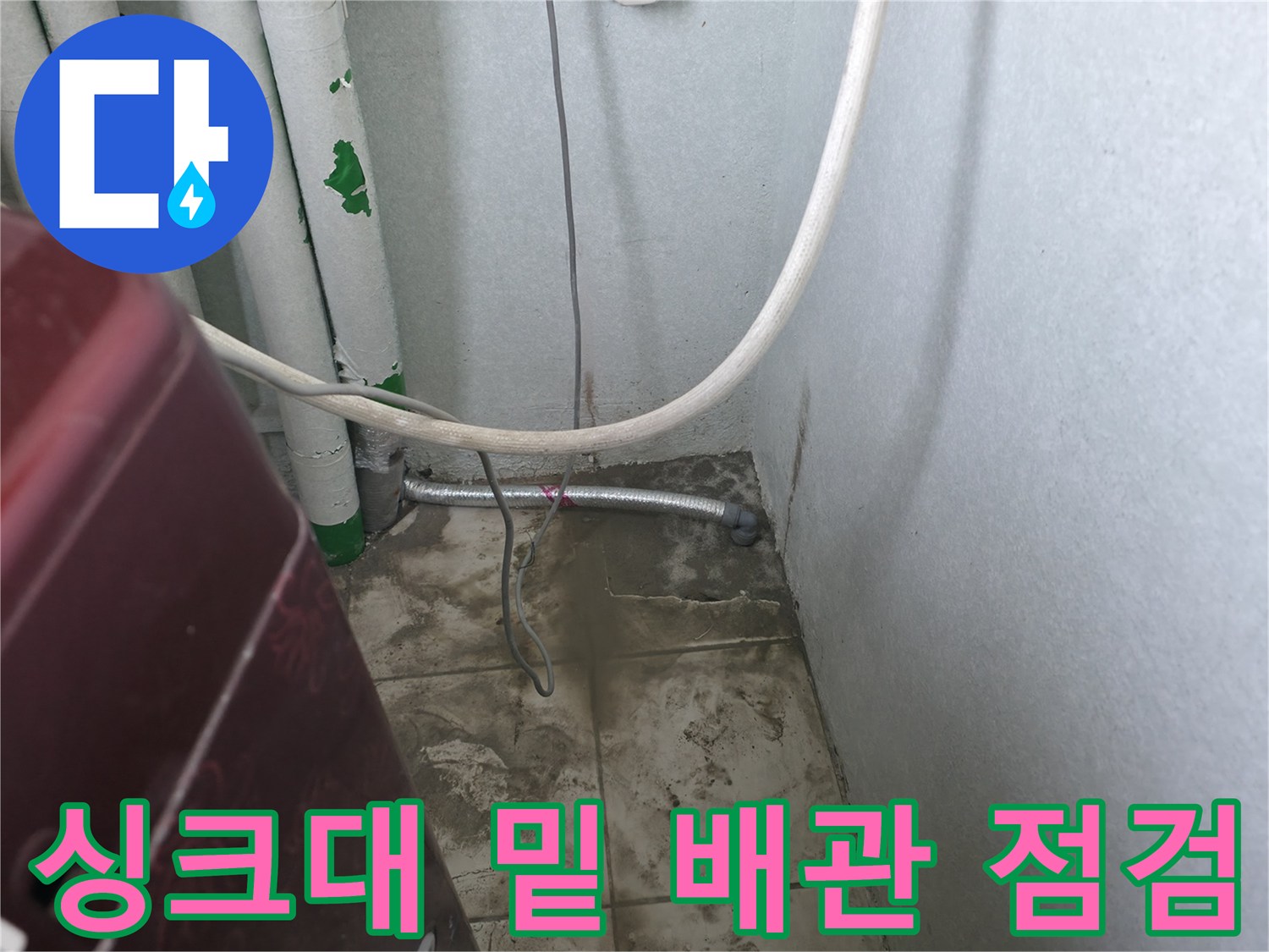 주방 하부장 내 노출된 수도 배관과 벽면 타일 상세 사진