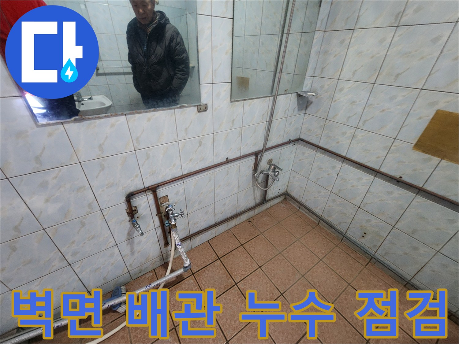 화장실 타일 벽면에 설치된 금속 배관과 수전 밸브 확인