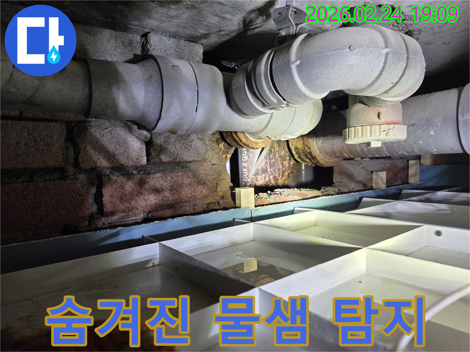 좁고-어두운-공간에-위치한-배관에서-누수가-발생하여-물이-고인-현장을-보여주는-사진