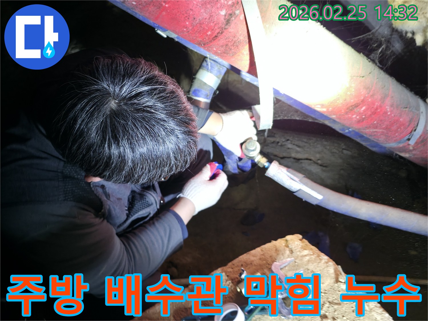 숙련된 누수 기술자가 좁은 공간에서 손전등을 비추며 주방-배수관 막힘 및 누수 지점을 정밀하게 점검하고-해결하고 있습니다-배수관누수해결-전문가수리