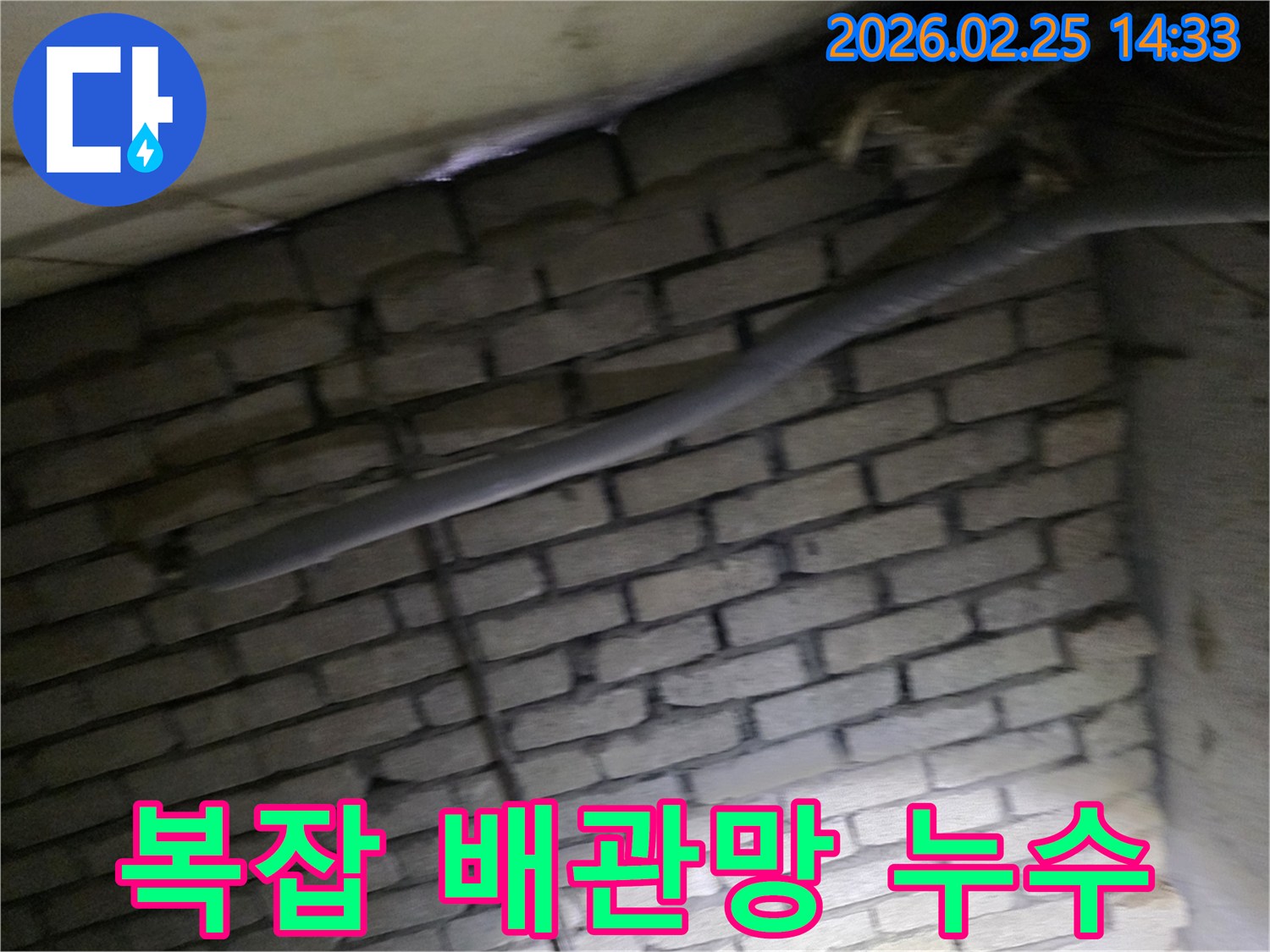 어두운 벽돌 벽면을 배경으로-복잡하게 얽힌 배관망에서-누수 지점을 탐지하기 위해-정밀하게 검사되는 현장 모습입니다.