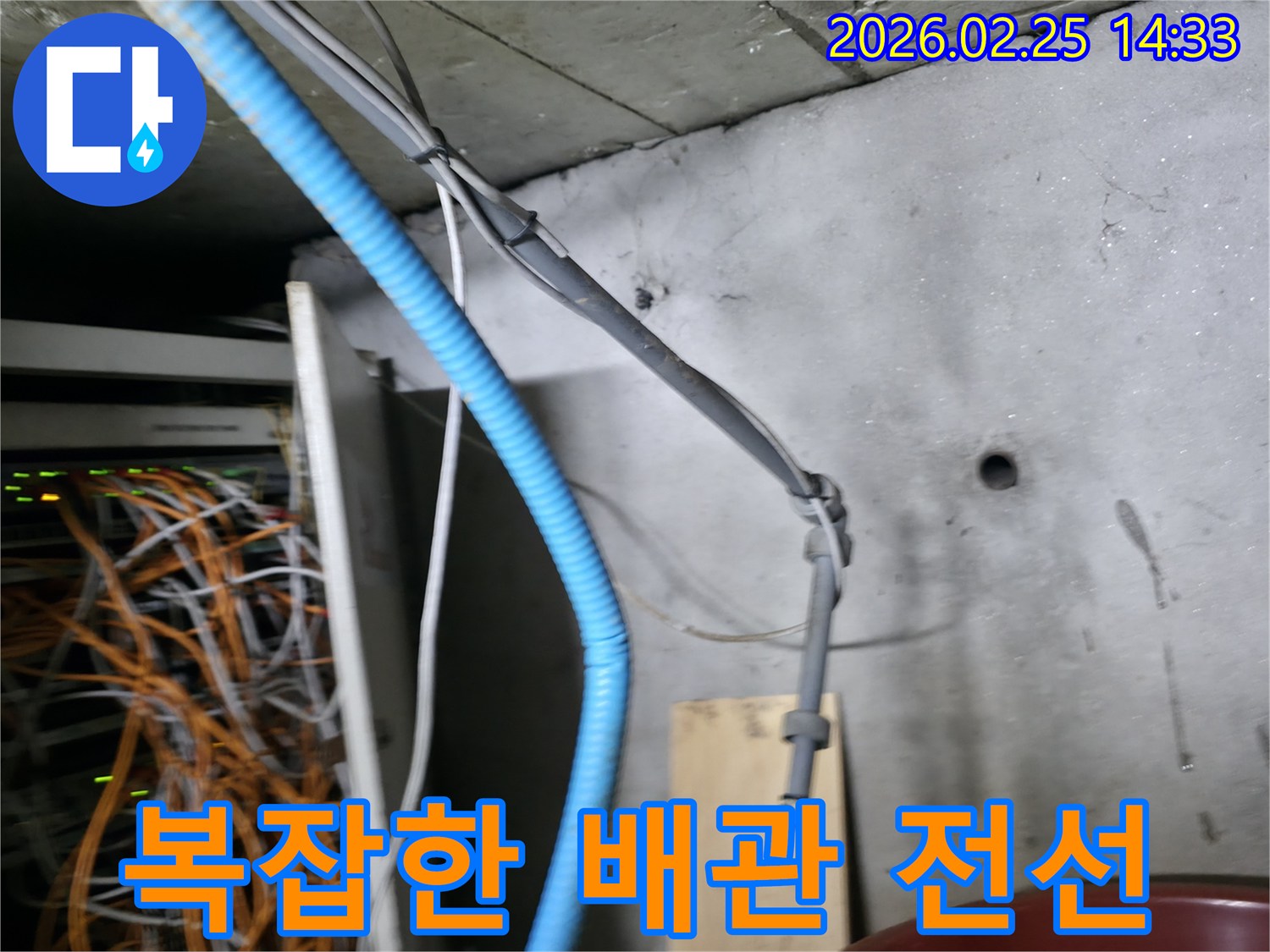 이 사진은 누수 공사 현장에서-콘크리트 벽면을 따라 설치된-다양한 배관과 전선들의-복잡한 모습을 보여줍니다