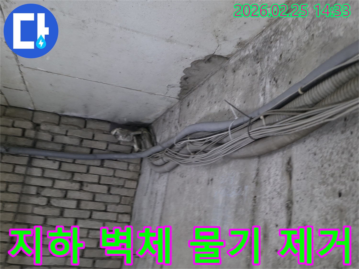 지하 벽면의-콘크리트와-벽돌 벽이 만나는-지점에서-발견된-오랜 누수로 인한-물자국과-주변의 복잡한 배관