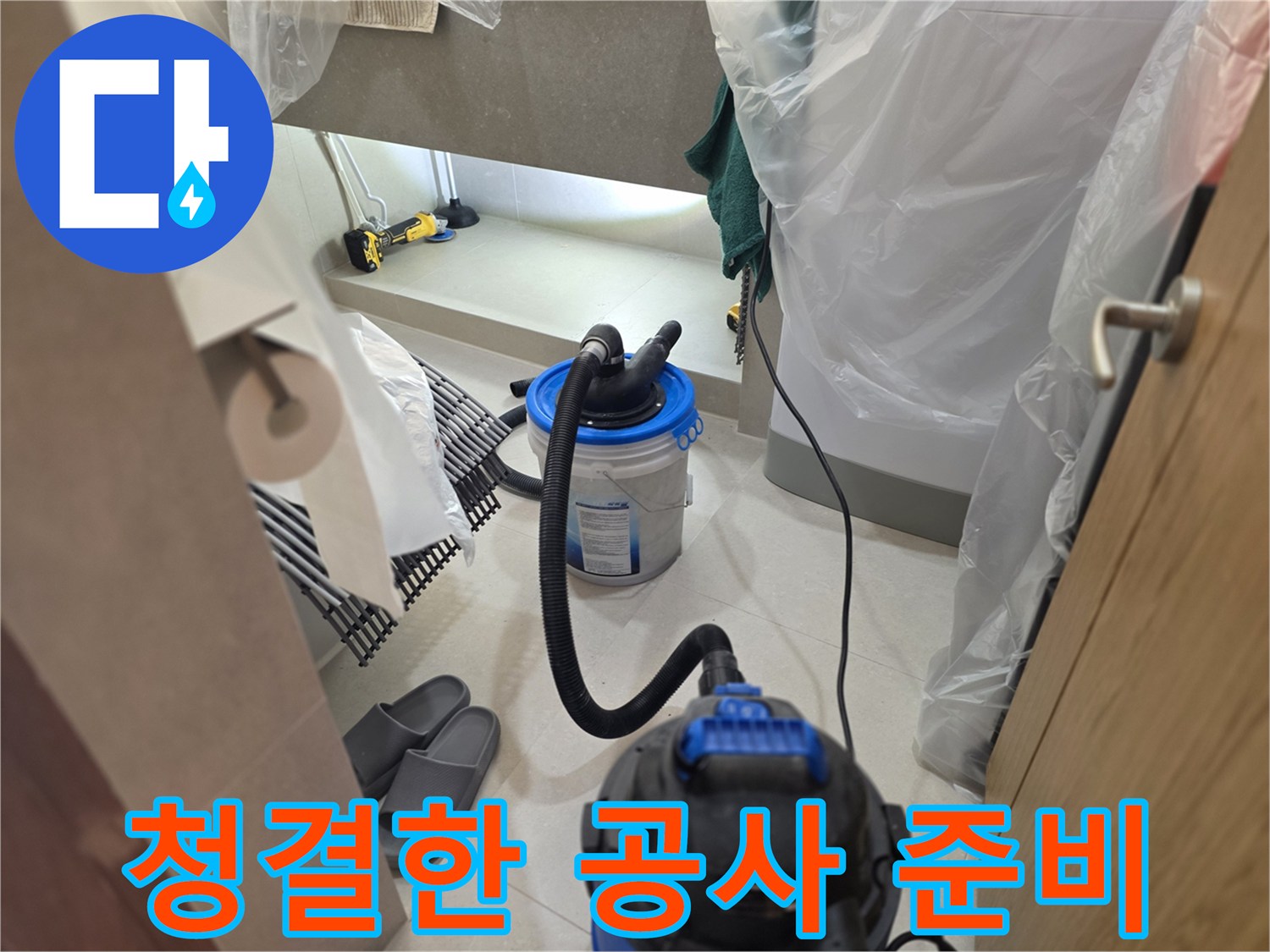 비닐 보양재와 청소기가 놓인 화장실 내부 작업 공간