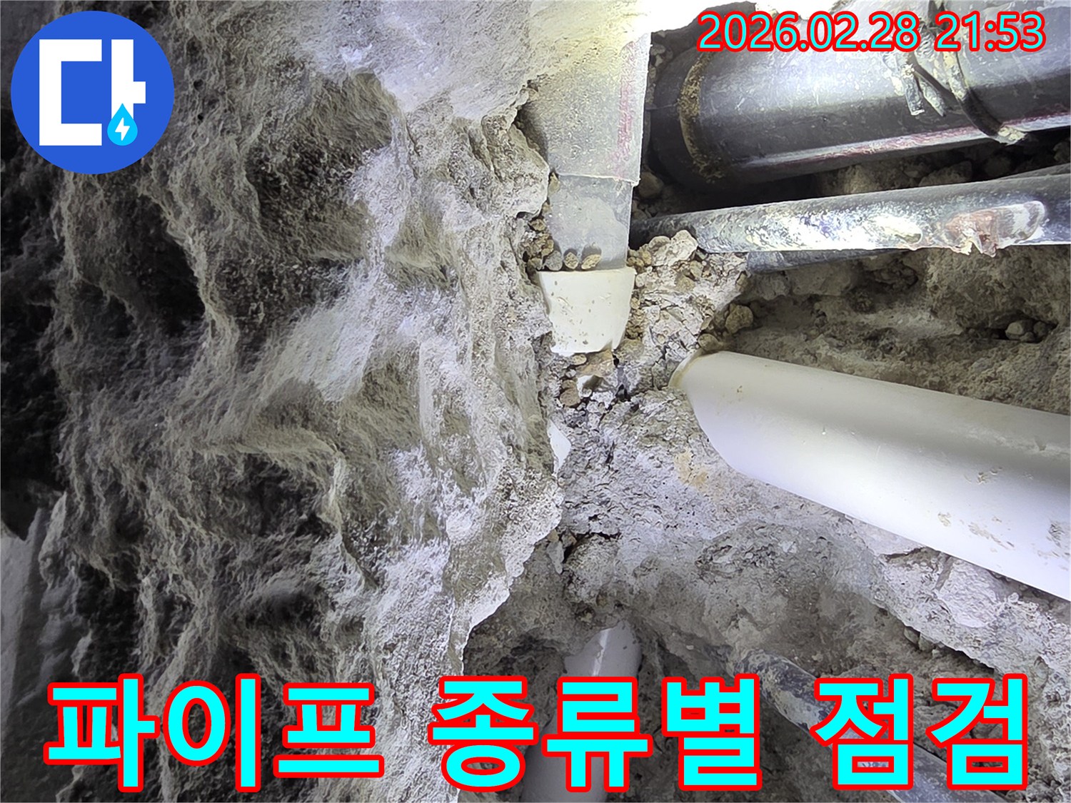 어두운 공간에서-흙과 자갈 속에 묻힌-다양한 종류의 배관들을-점검하는 누수 전문가의 모습
