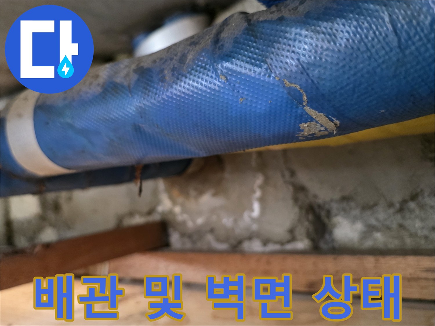 콘크리트 벽과 파란색 배관의 접합부 근접 촬영