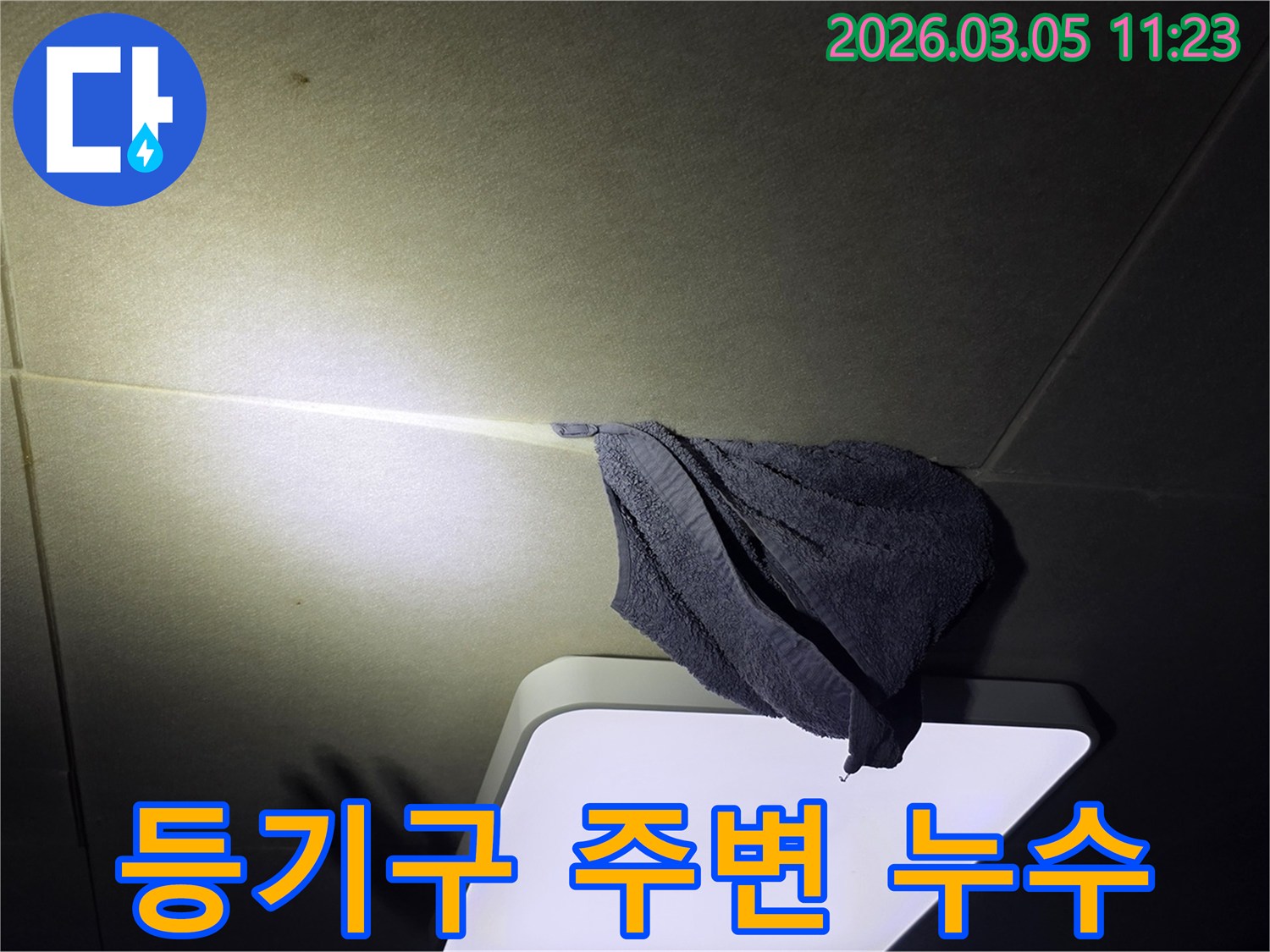 누수로-인해-천장-등기구-주변에-물이-떨어져-수건으로-임시-조치한-모습을-담은-사진