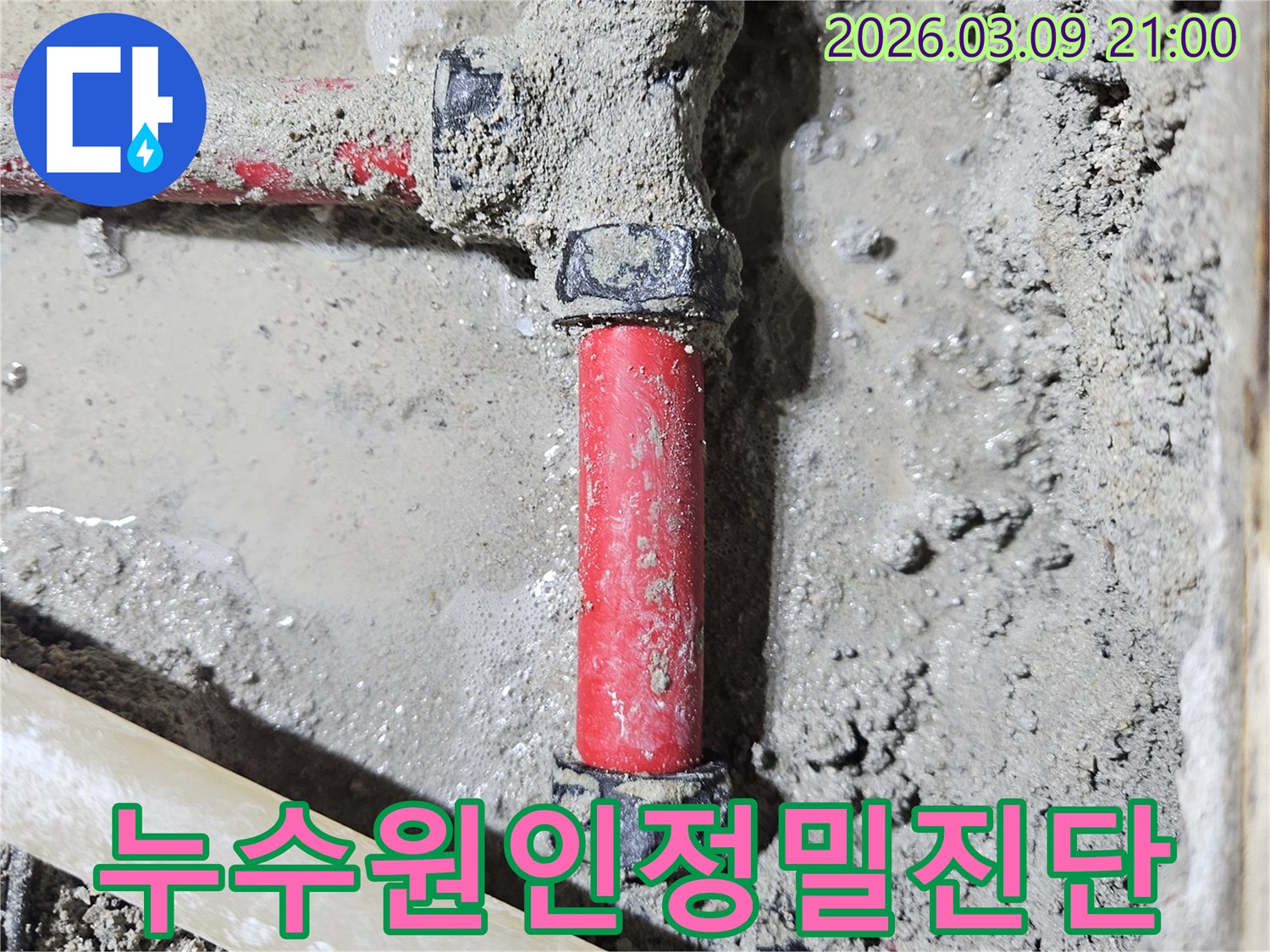 젖은 시멘트 바닥에-매립된 빨간색 배관의-누수 지점을-첨단 장비로-정확히 진단한-모습입니다