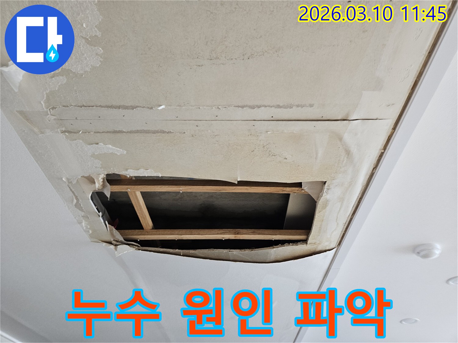 이 이미지는-천장 누수로 인해-벽지가 심하게 손상되어-내부 구조가 드러난-피해 현장을 보여줍니다-누수 엔지니어가-정확한 원인 파악을 위해-천장 일부를 개방한 모습입니다.