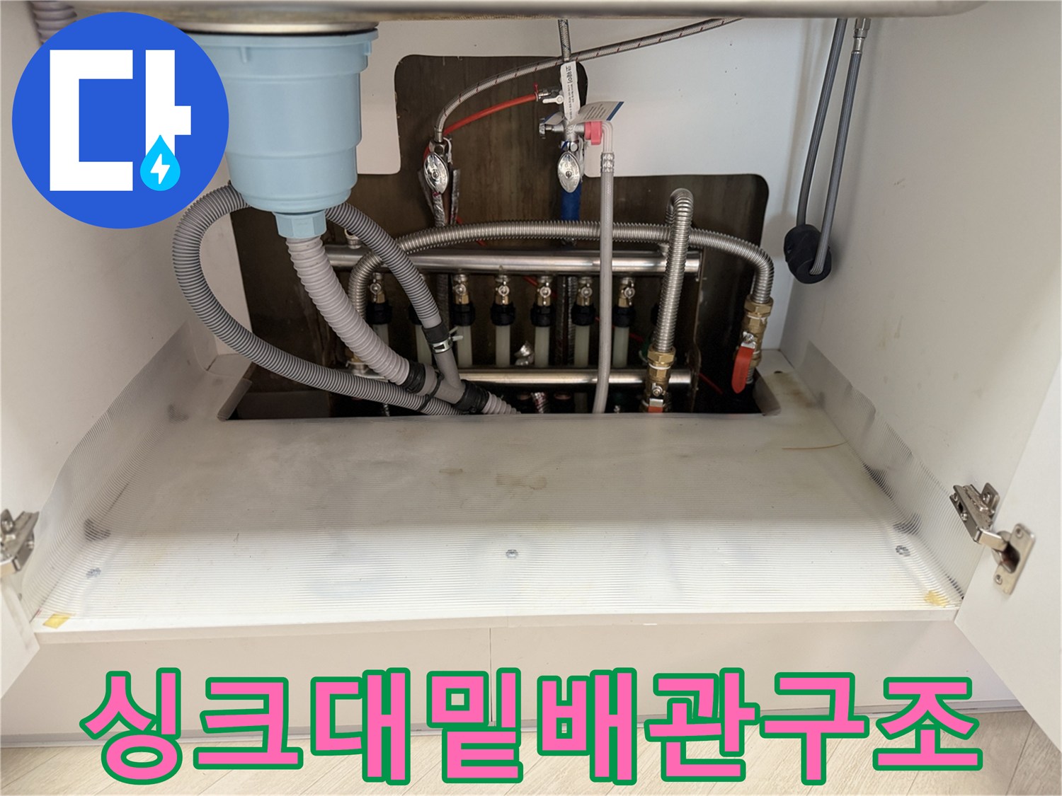 싱크대 아래에 노출된 분배기와 다수의 배관 연결부