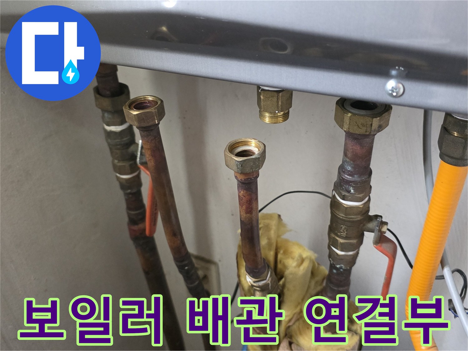 금속 소재의 밸브와 유연한 호스가 연결된 보일러 하부 모습입니다.