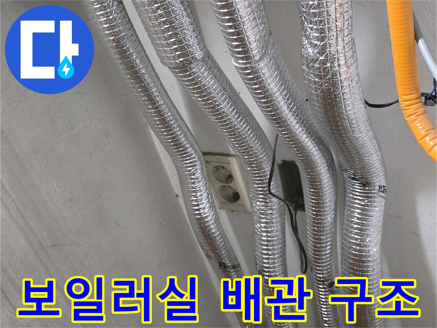 보일러실 내부에 설치된 은색 보온 배관과 전기 콘센트 부근