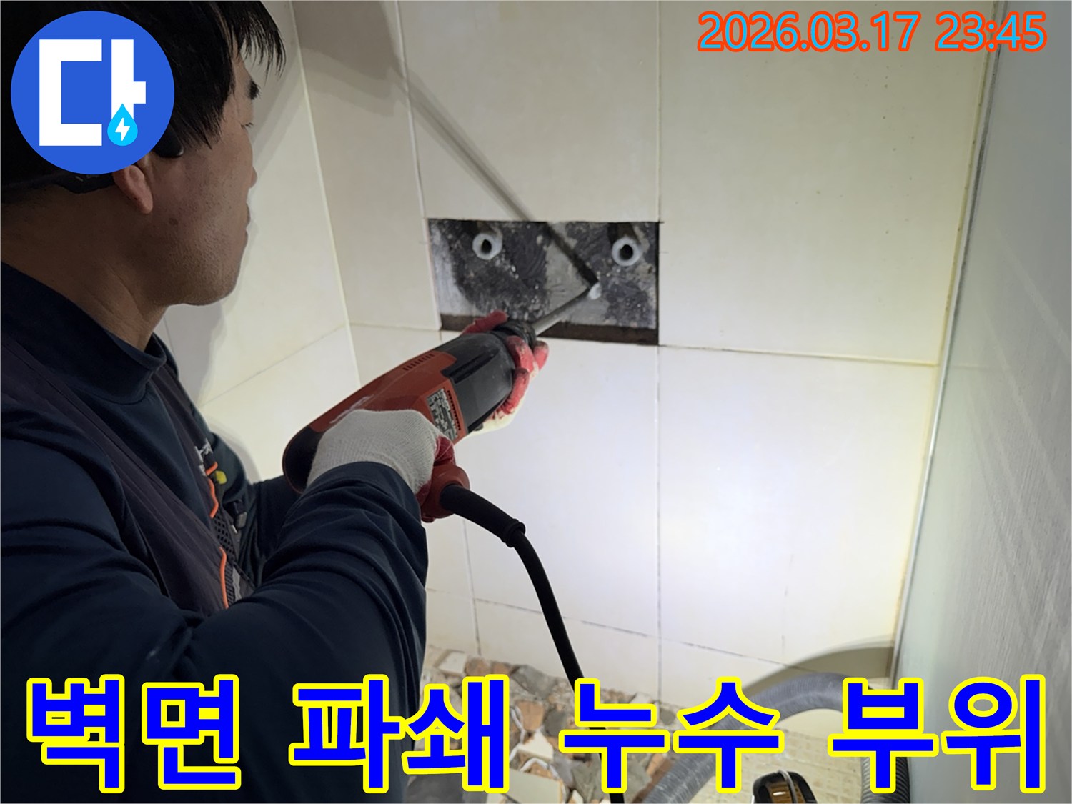 숙련된 기술자가 누수 지점을 찾아내기 위해-벽면 타일을 깨고 내부 배관을 드러내는 작업을 진행하고 있습니다.