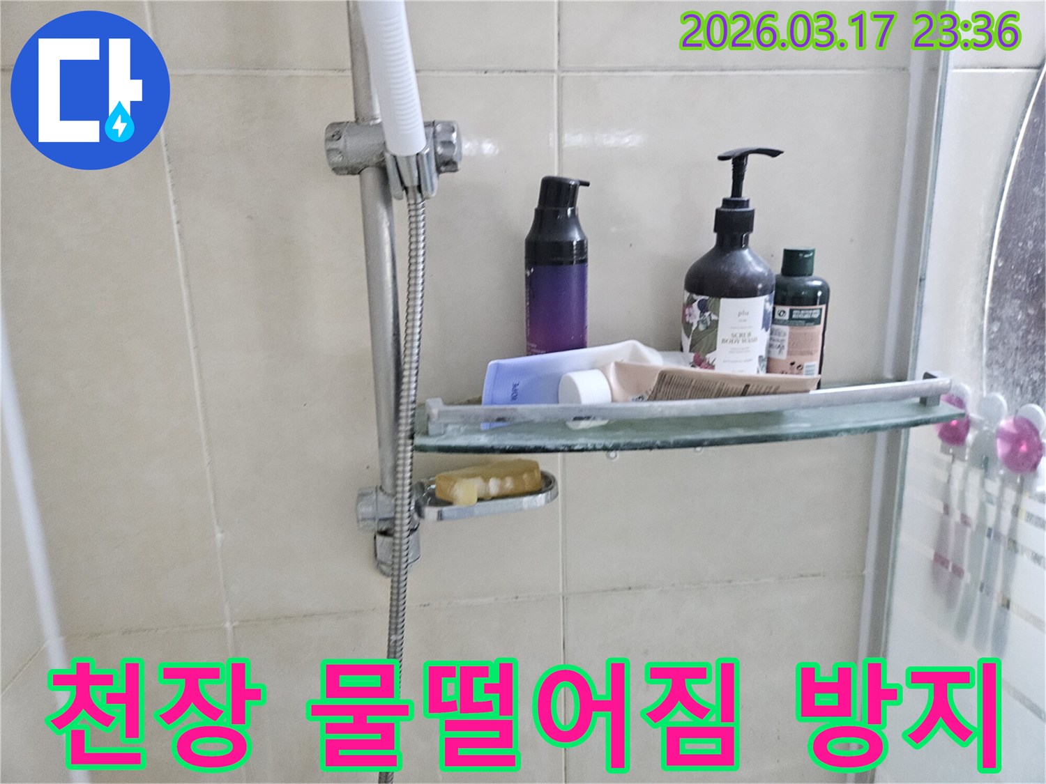 화장실 샤워기 옆-유리 선반에 맺힌 물방울은-천장 물떨어짐의 간접적인 증거를 보여주는 이미지입니다